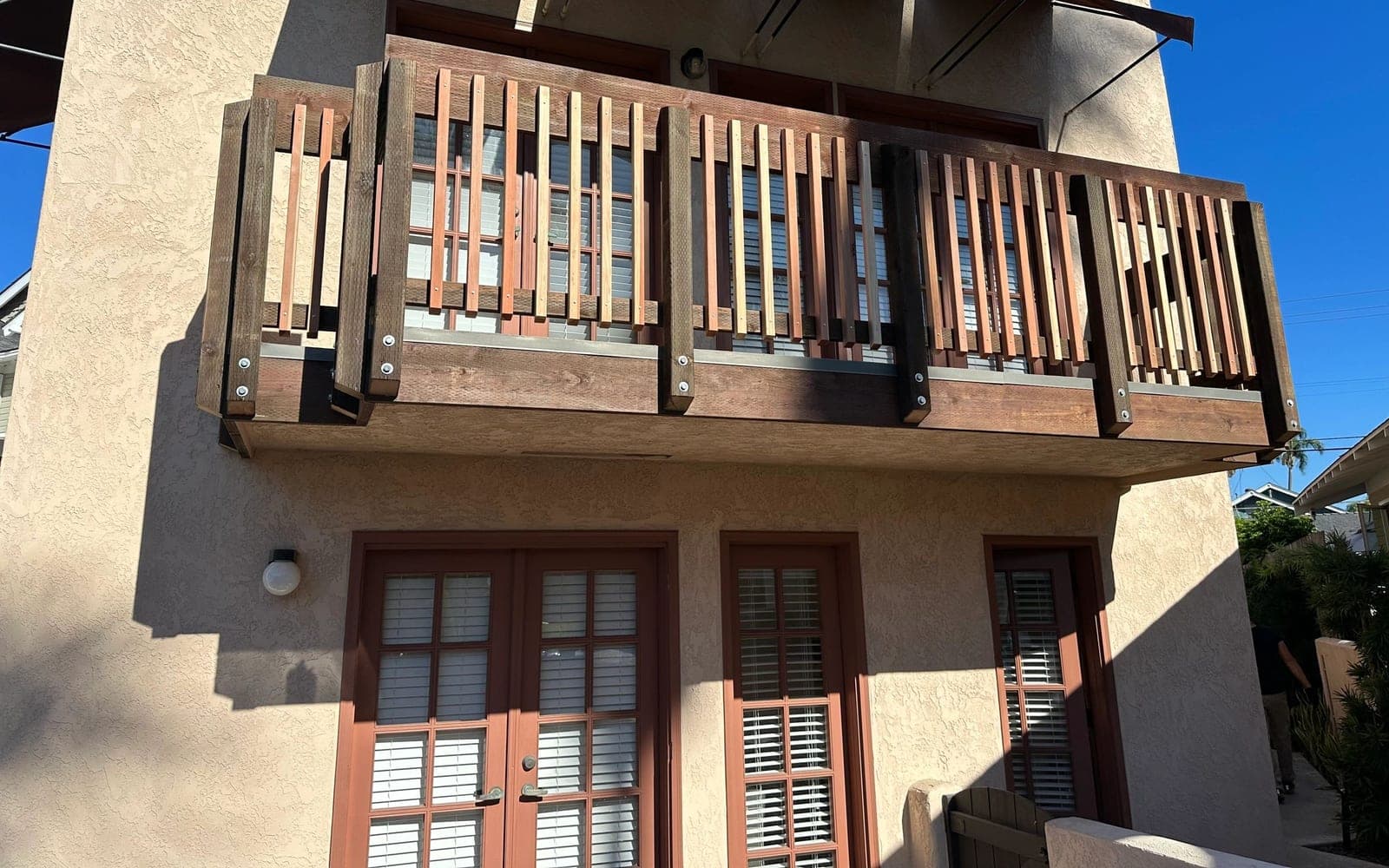 Completed All World Construction balcony repair with wood railing and exterior finish work